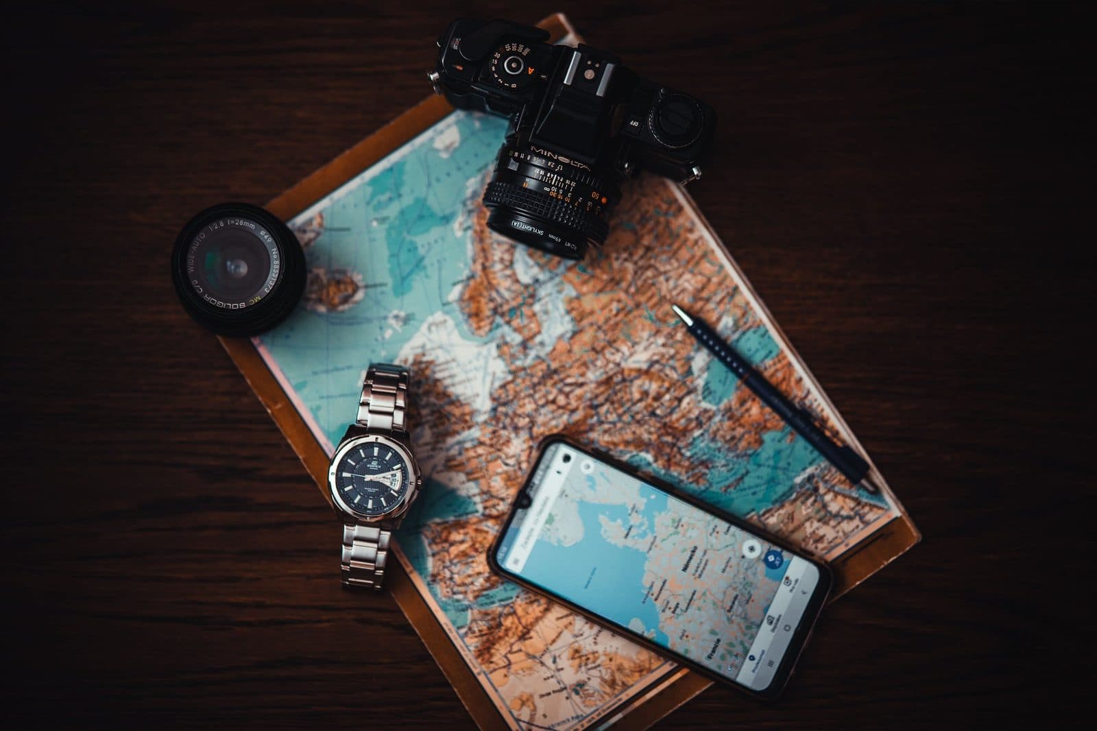 Смартфон с картой, часы и фотоаппарат на бумажной карте